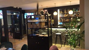 A bar area with stools, a counter, and shelves stocked with bottles. - Hostal Rocamar (Santander)