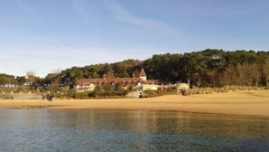 A lakeside property with a large house featuring a prominent tower and multiple roofs. - Hostal Rocamar (Santander)
