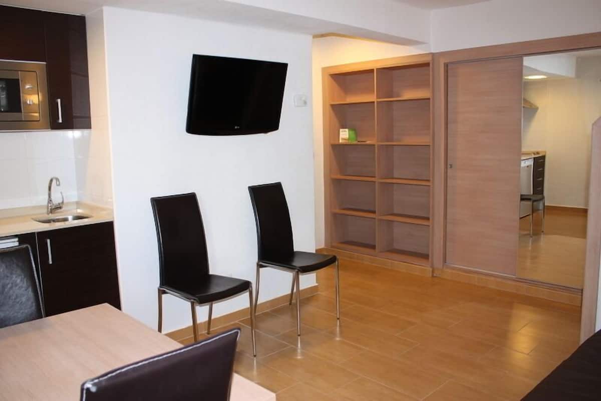 A modern kitchen with a flat-screen TV, a dining area with two chairs, and a sliding door closet.