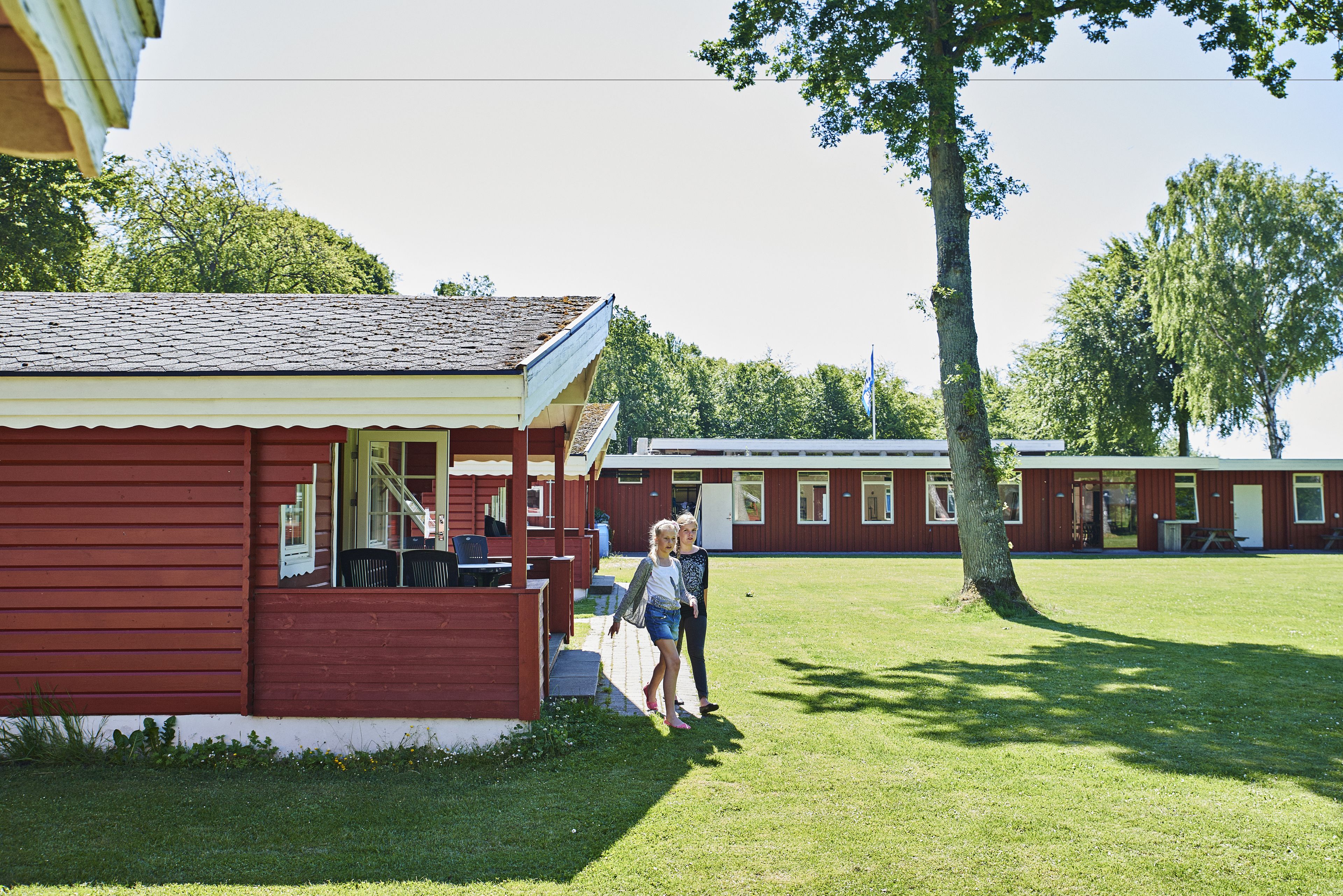 A red building with a porch and a grassy area in front.