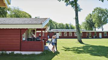 A red building with a porch and a grassy area in front.