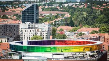 A modern building with a glass facade and a colorful circular structure in the foreground.