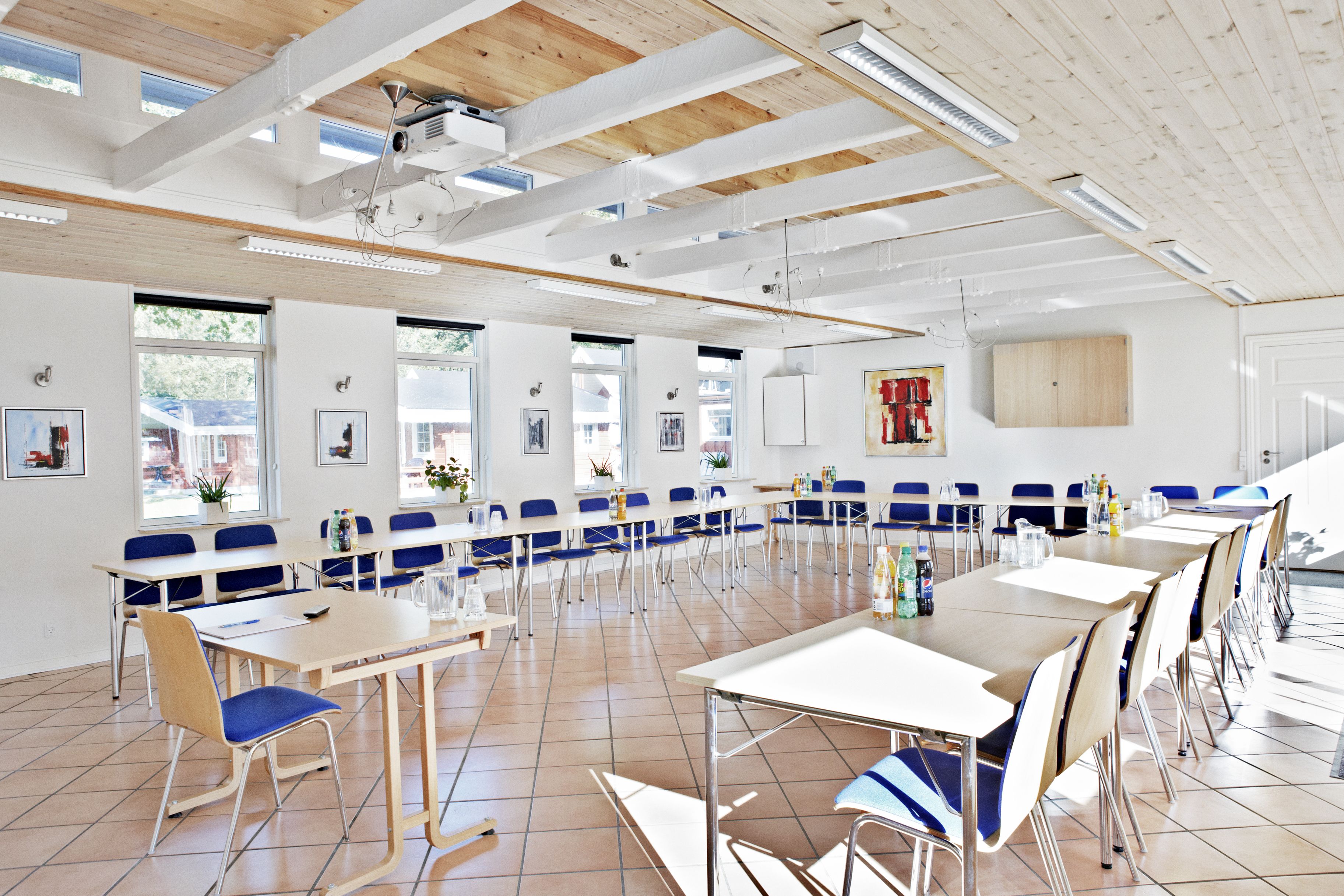 A spacious dining area with high ceilings, large windows, and modern furniture.