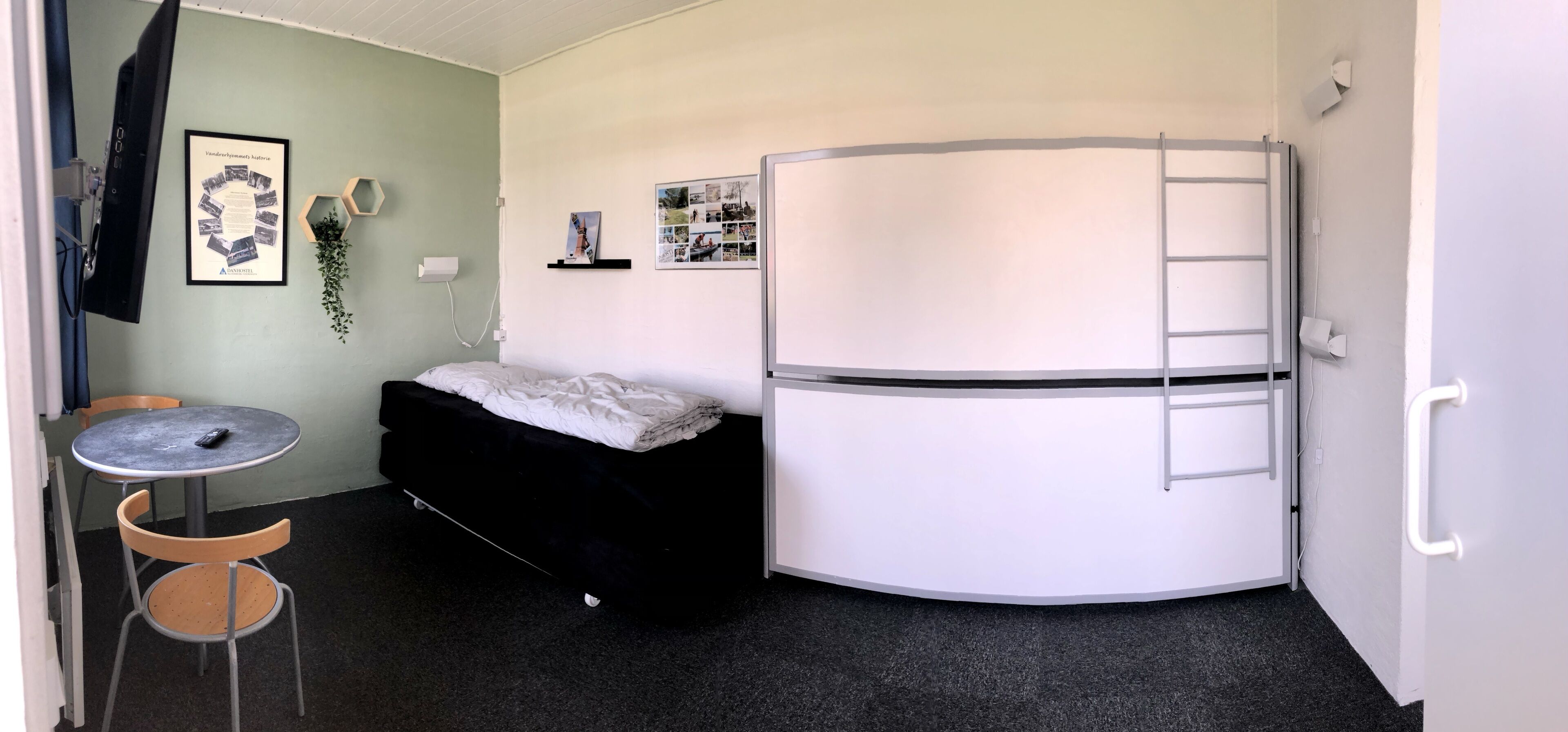 Una habitación compacta con una cama, una mesita pequeña y un armario blanco que incluye una escalera.