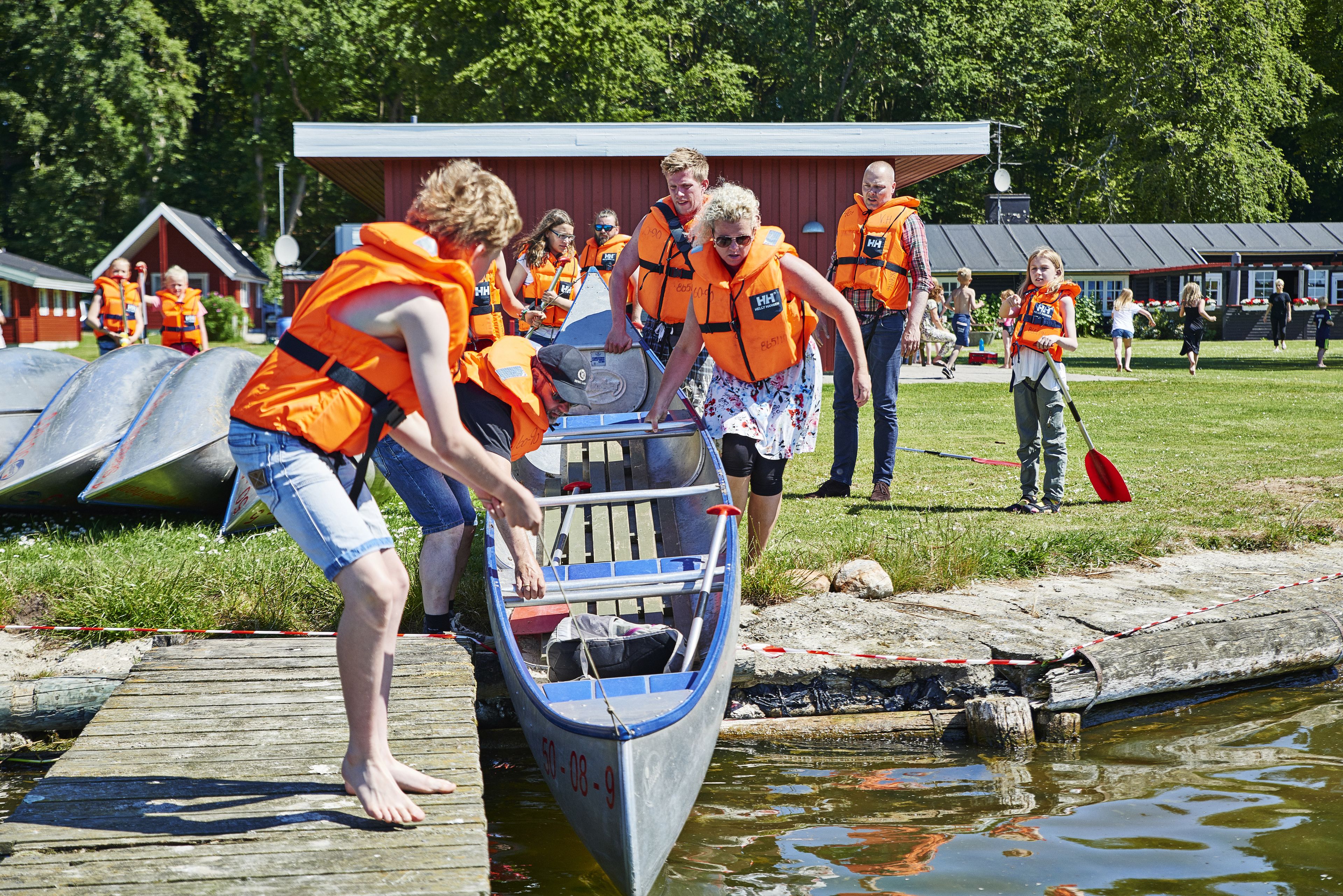 A group of people in orange life jackets loading a boat onto a dock.