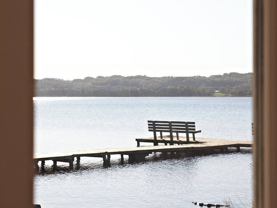 Vista de un lago con un muelle de madera y una banca.