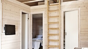 Een houten interieur met een hoogslaper, een ladder, een televisie en een bank.