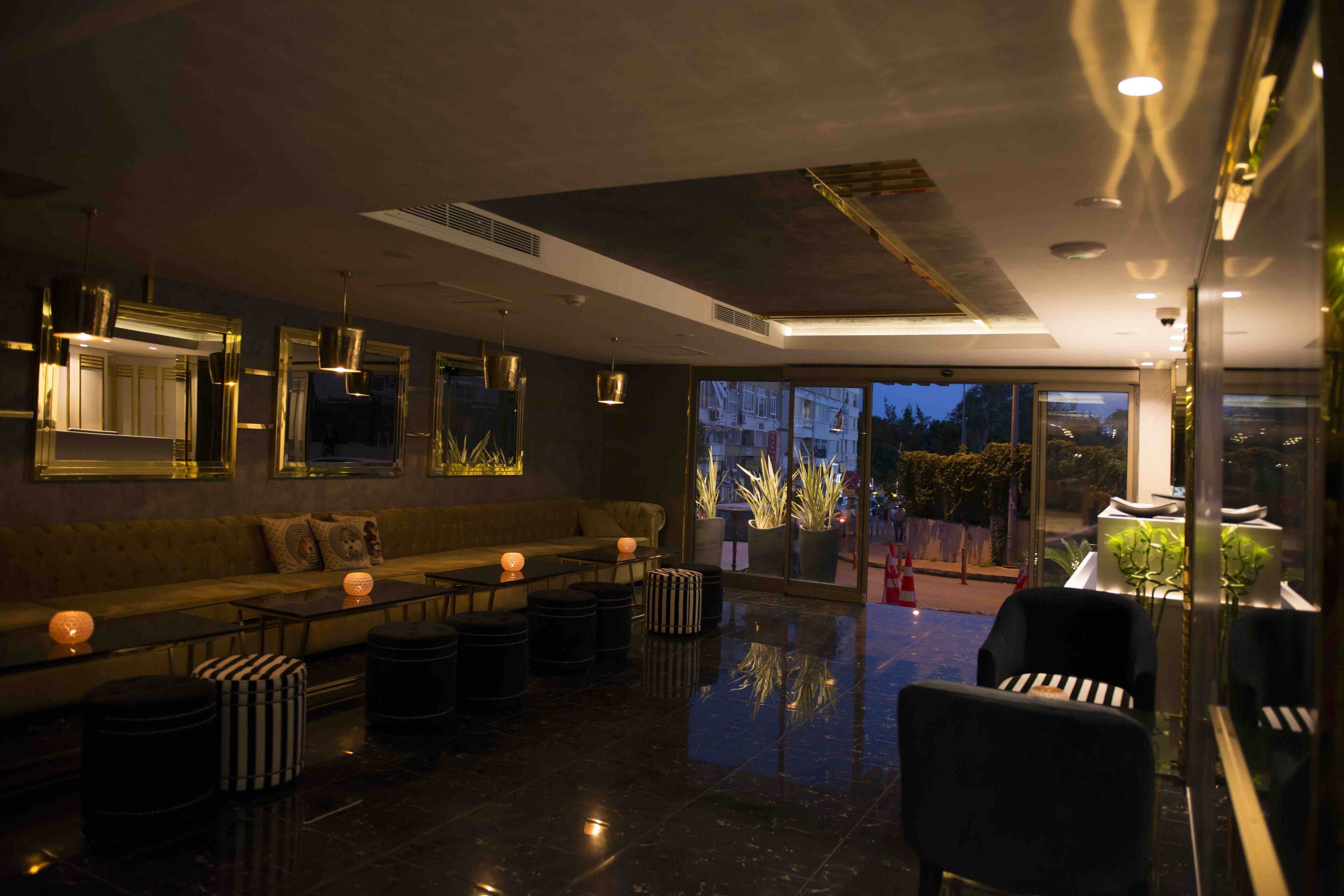 A modern lounge area with a sofa, ottomans, and a glass partition.