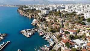 A coastal cityscape with a marina, buildings, and mountains in the background. - Sky Kamer Hotel (Antalya)