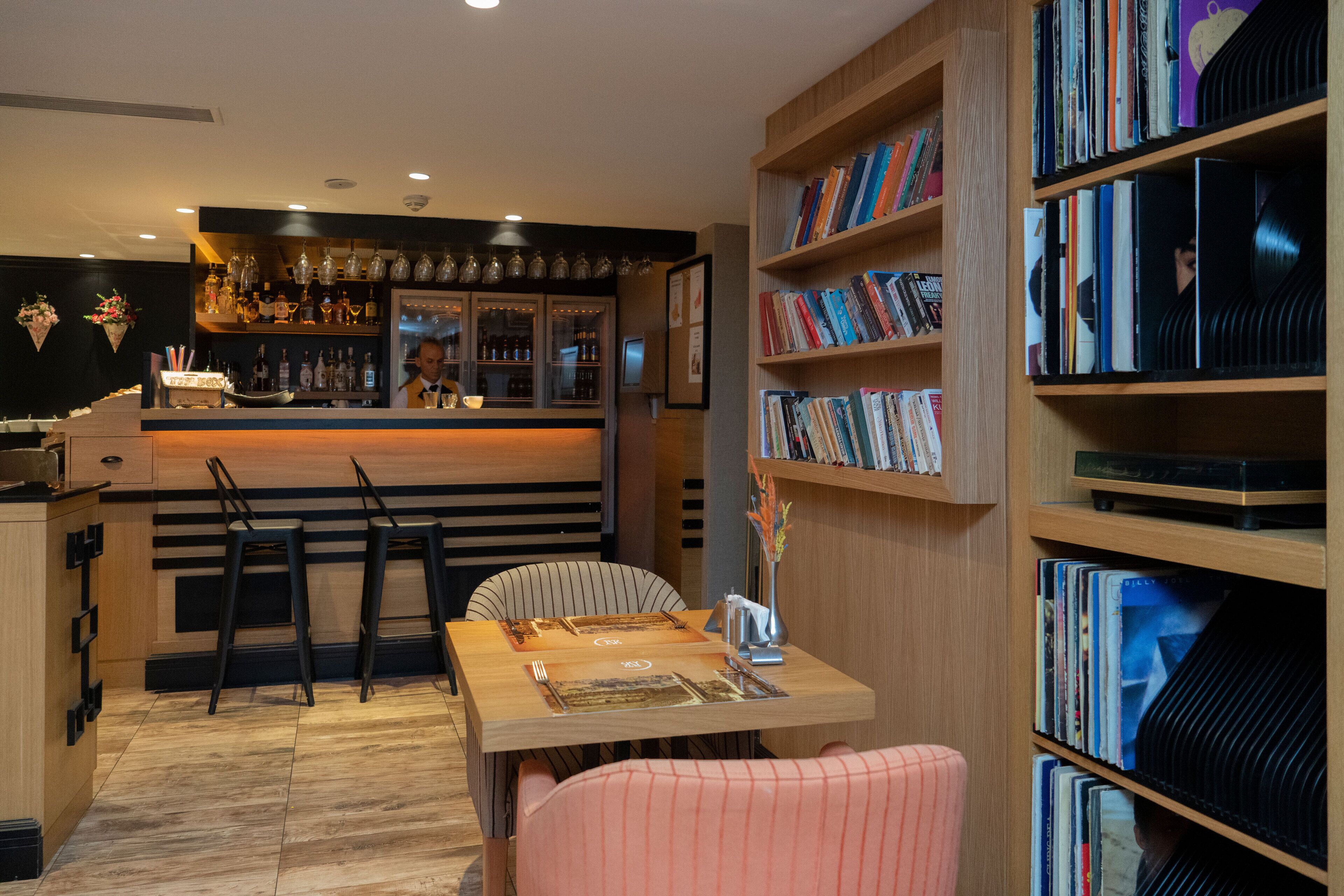Un espace bar avec un comptoir, des tabourets et une bibliothèque remplie de livres.