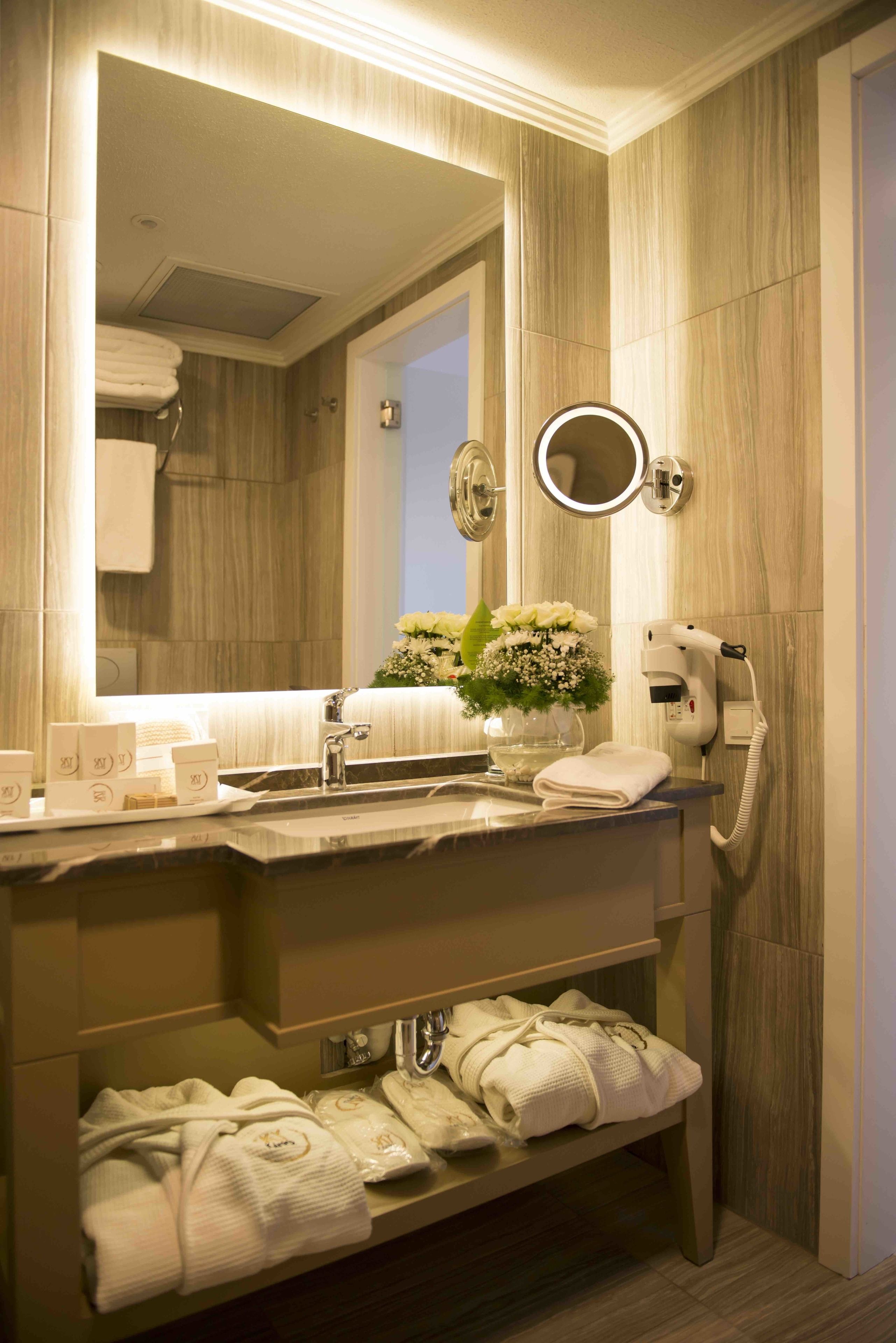 Un baño moderno con un espejo grande, un secador de pelo y toallas ordenadas en un estante.