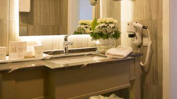 Un baño moderno con un espejo grande, un secador de pelo y toallas ordenadas en un estante.