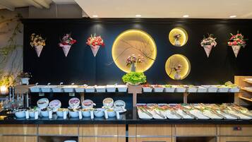 A buffet setup with multiple serving stations, a variety of dishes, and decorative floral arrangements.
