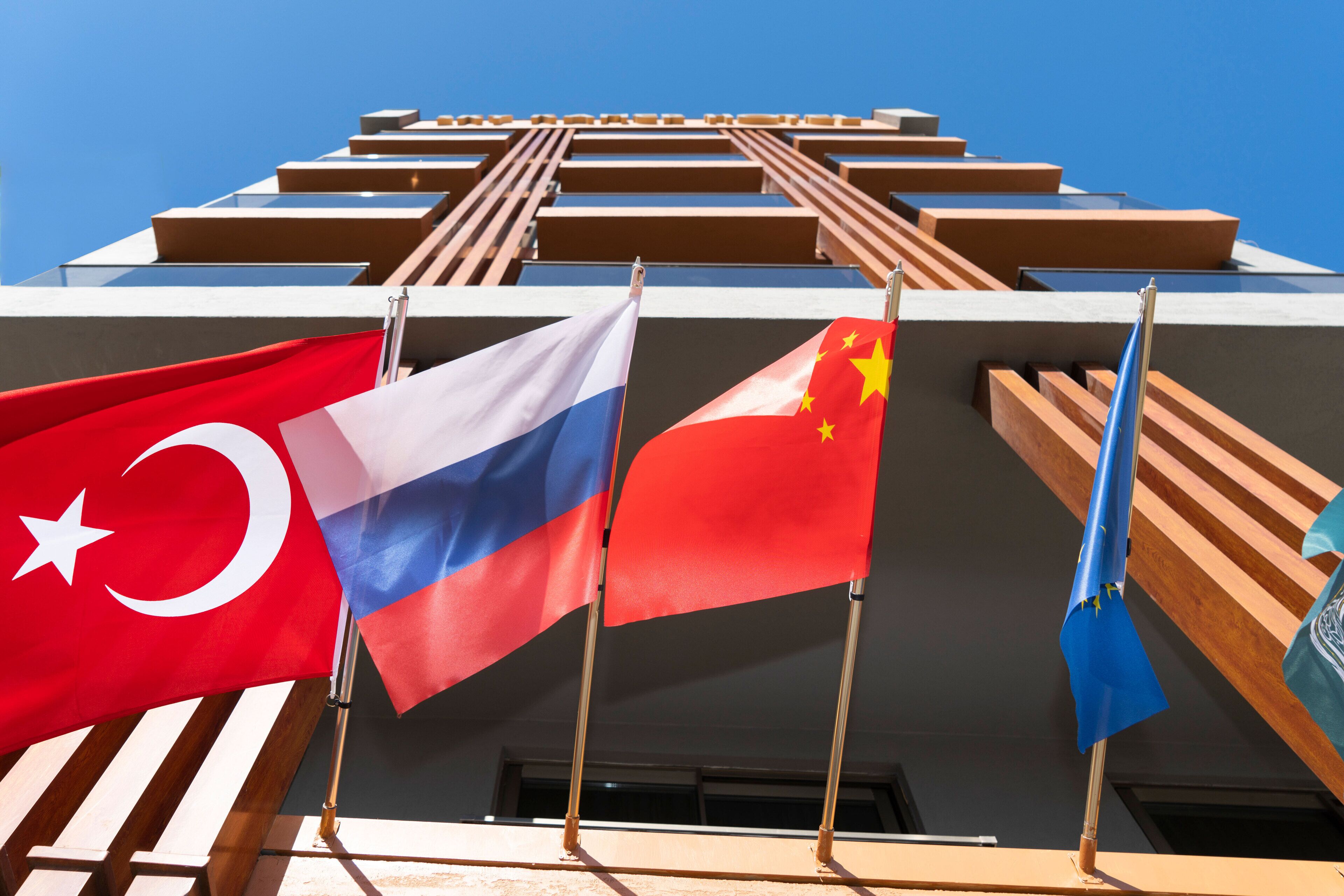Un edificio con múltiples banderas, incluyendo las de Turquía, Rusia y China, y un diseño de listones de madera.