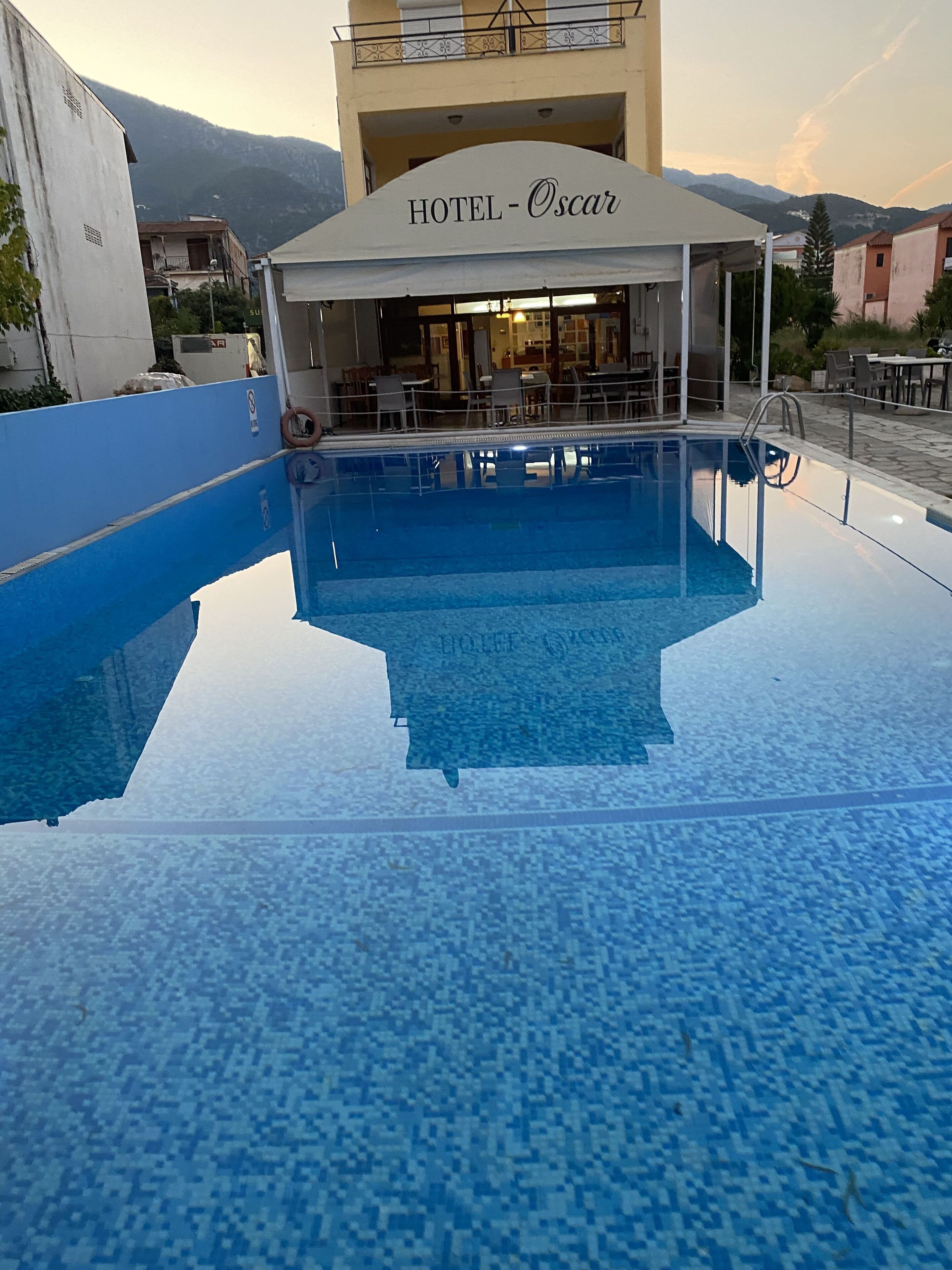 Um hotel chamado 'HOTEL - Oscar' com área de piscina e mobiliário para área externa.