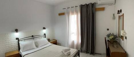A clean, well-lit bedroom with a bed, bedside tables, a dresser, and a mirror.