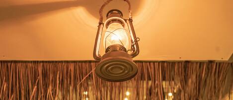 Un farol colgando del techo en una habitación con techo de paja.