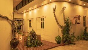 Un espacio interior bien iluminado con suelo de madera, plantas en macetas y una estructura de madera rústica.