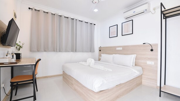Una habitación de hotel con cama, escritorio, silla, televisor y ventilador de techo.