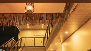 Una escalera con barandilla, un farol colgante y techo de madera.