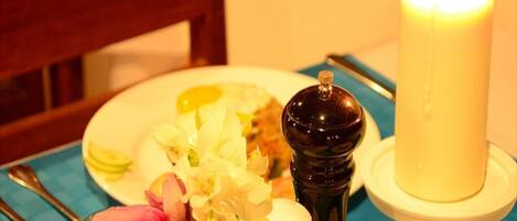A table with a candle, a salt and pepper shaker, and a plate with food and flowers.
