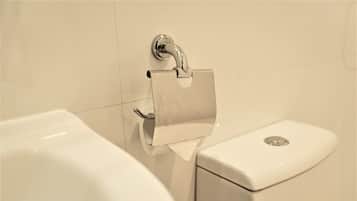 A toilet paper holder mounted on a wall next to a toilet.