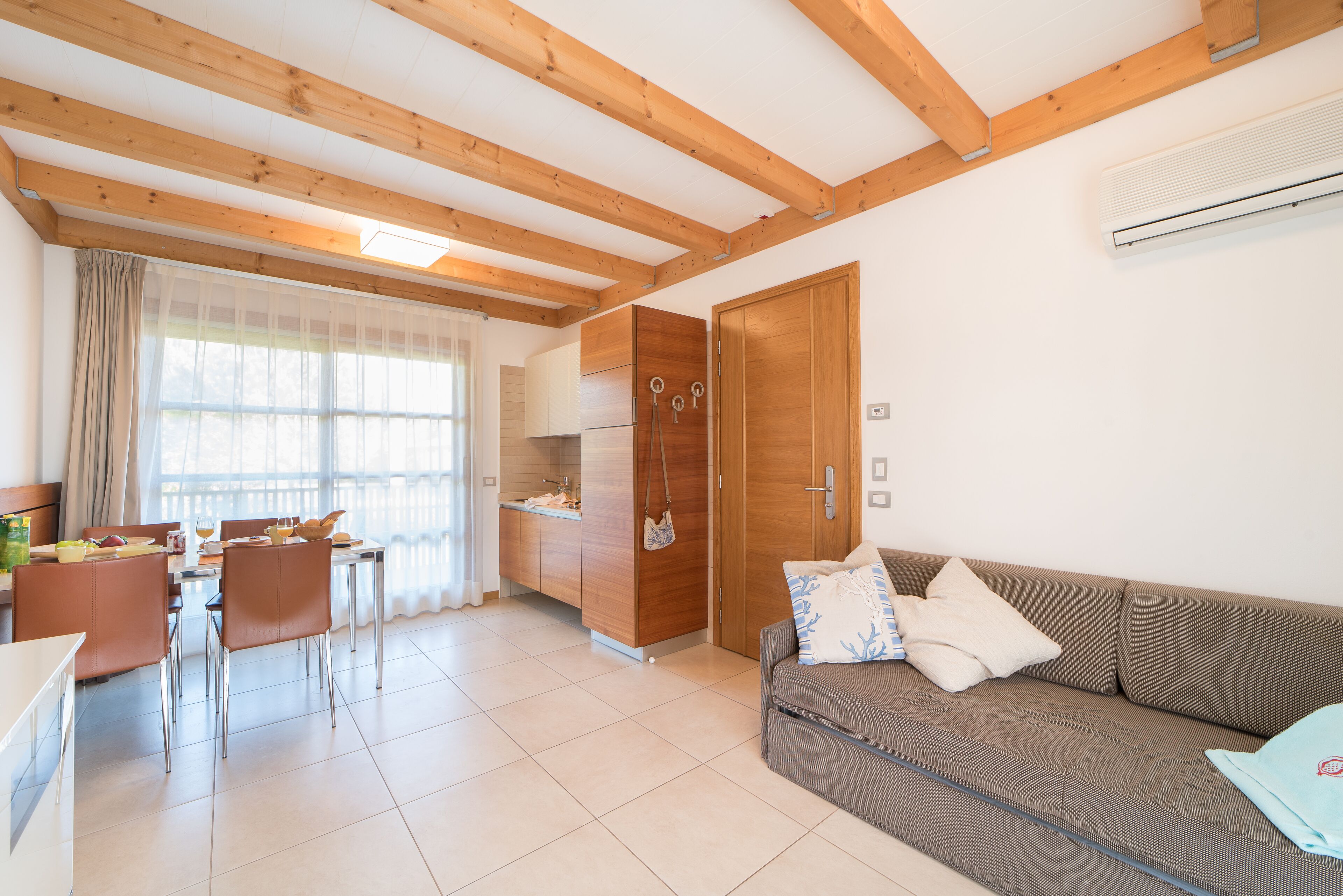 A modern living space with a dining area, kitchenette, and a sofa with cushions.