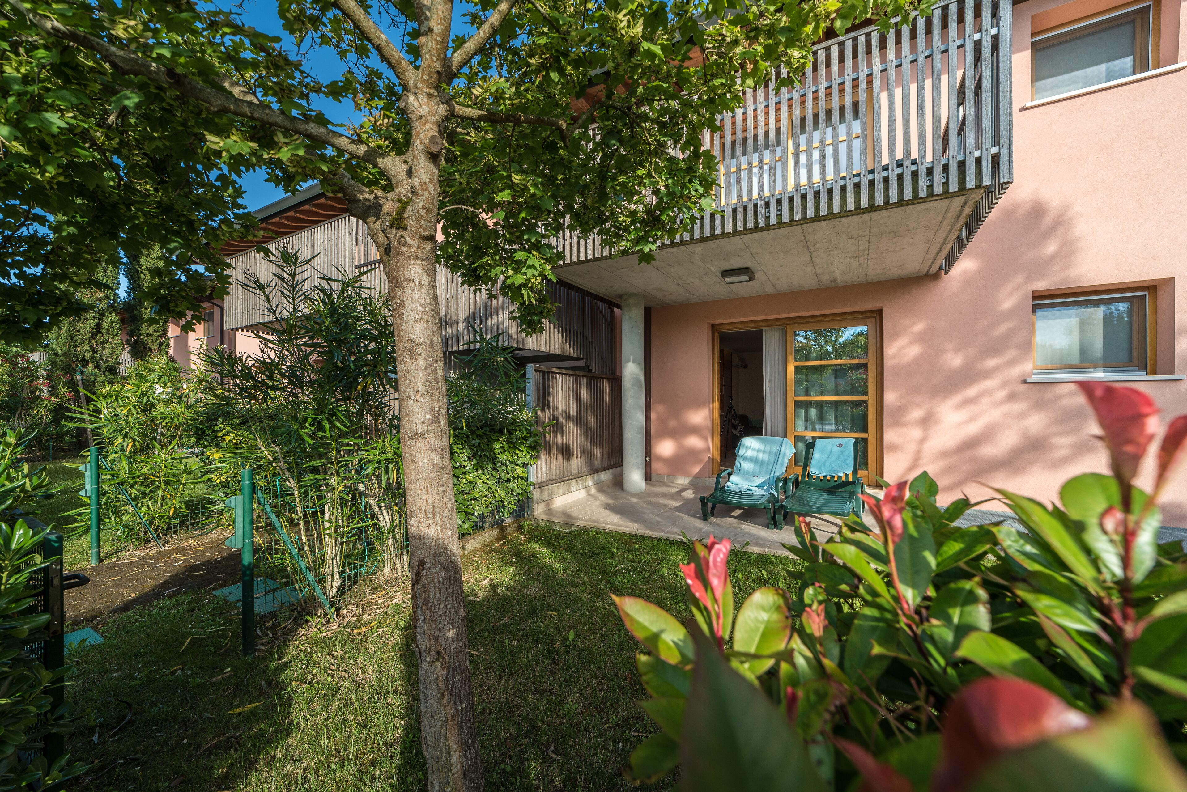En boligbygning med balkon, lille have og sti.