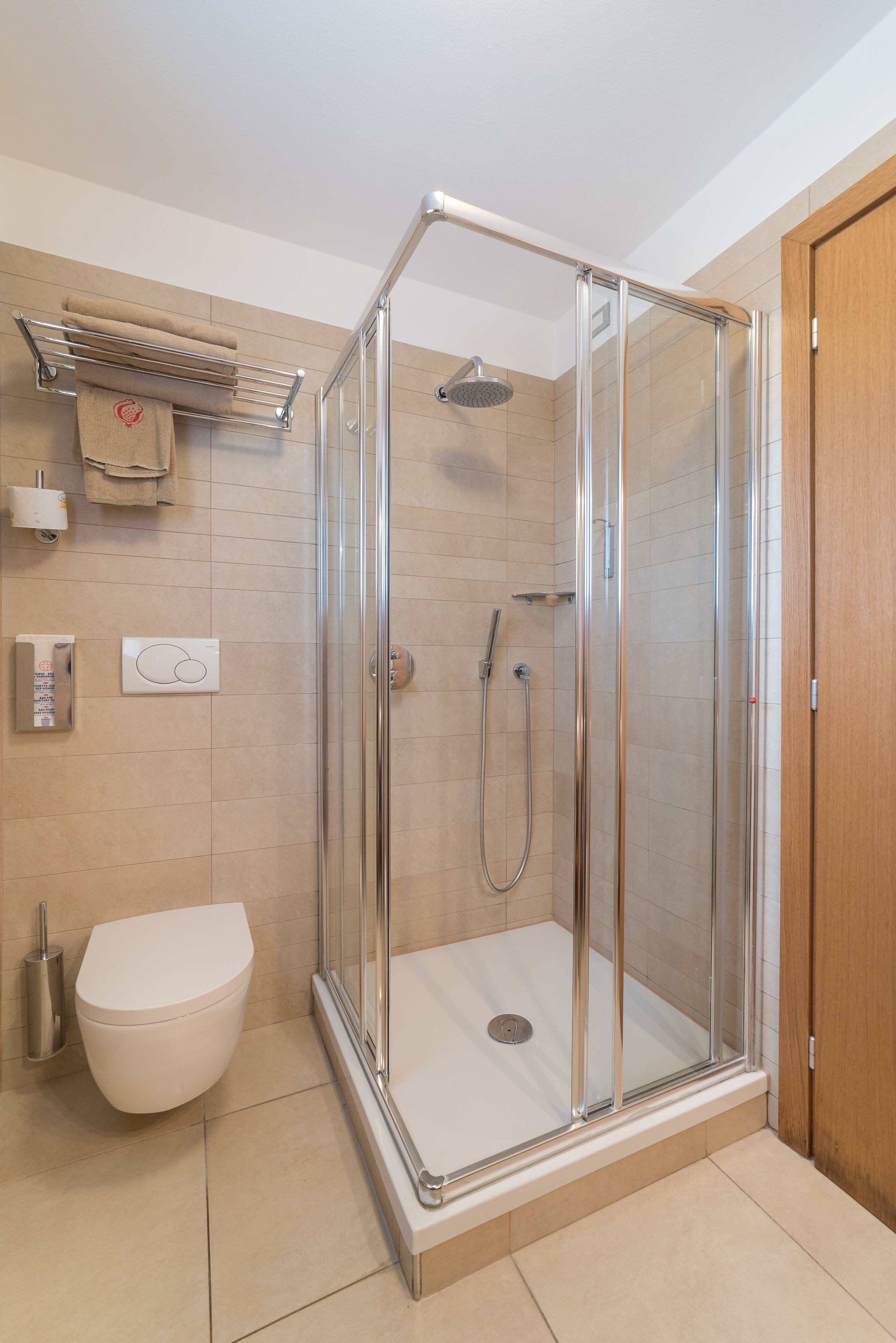 A modern bathroom with a glass-enclosed shower, a toilet, and a towel rack.