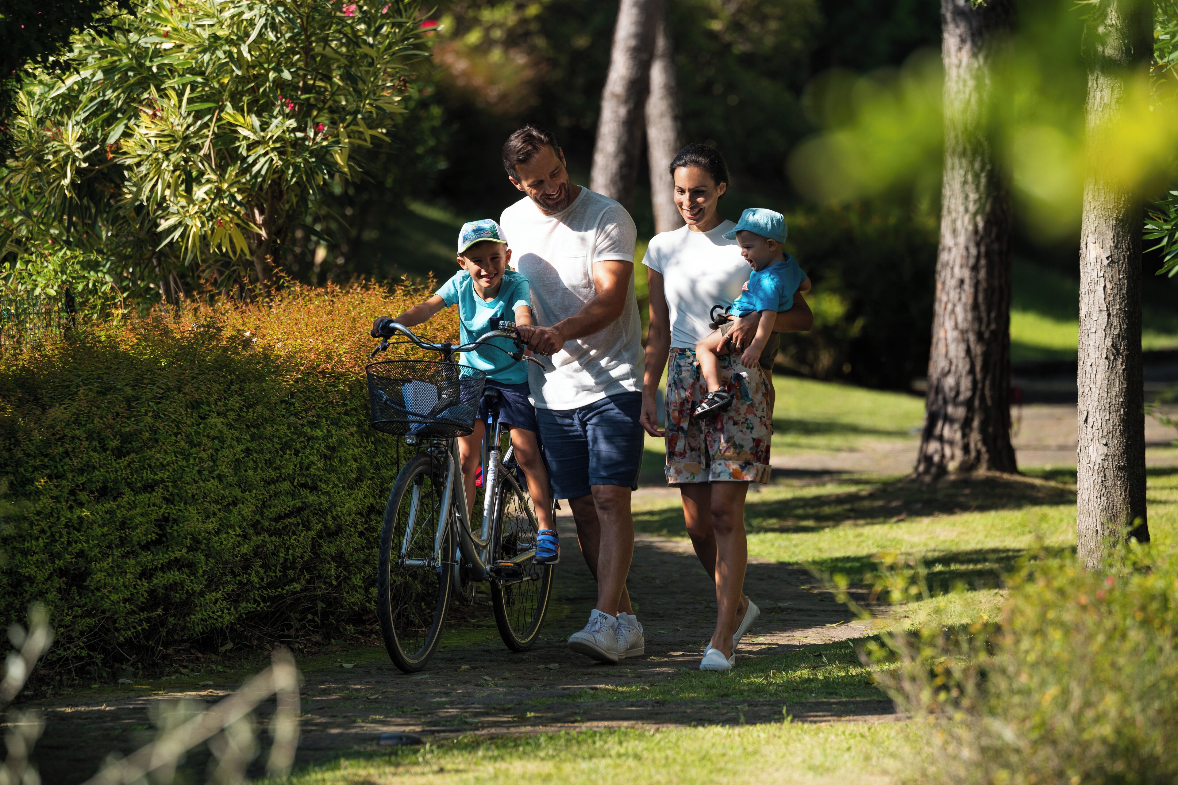 Une famille se promène dans un parc, un vélo à la main.