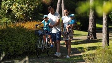 Une famille se promène dans un parc, un vélo à la main.