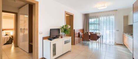 A modern hotel room with a kitchenette, a dining area, and a separate bedroom.
