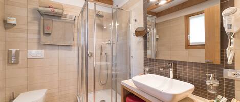 Une salle de bain moderne avec une douche à parois de verre, un lavabo blanc et une boîte de rangement rouge.