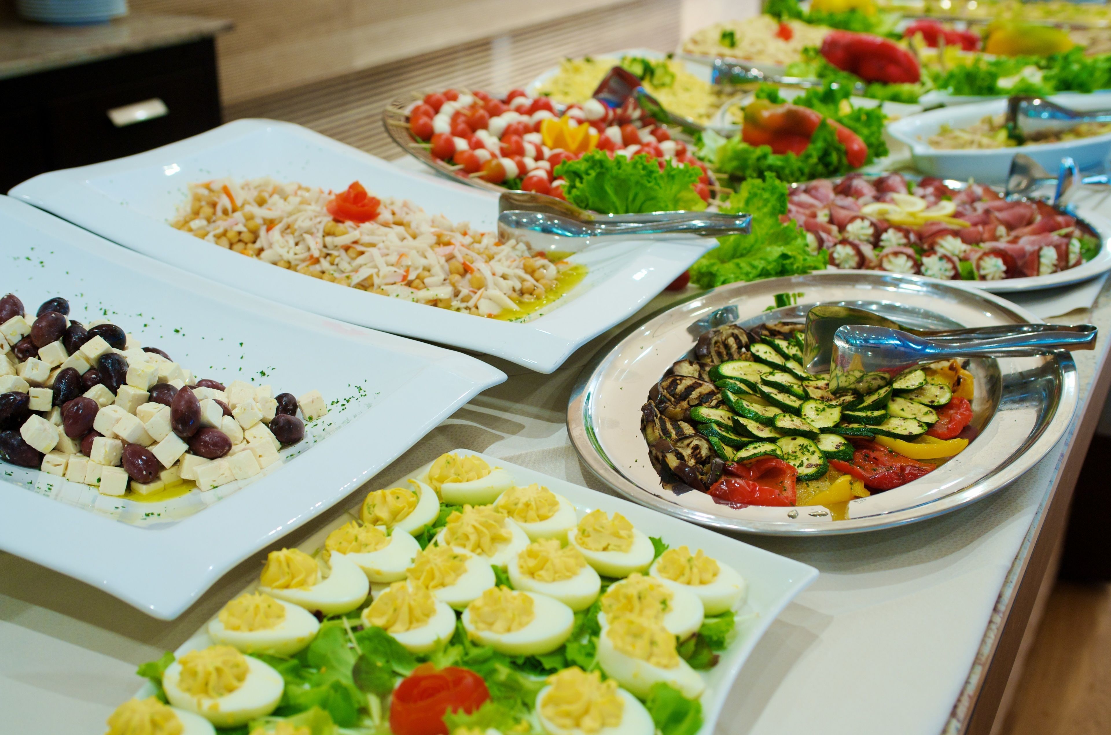 Un bufé con diversos platos, incluyendo ensaladas, verduras y huevos.
