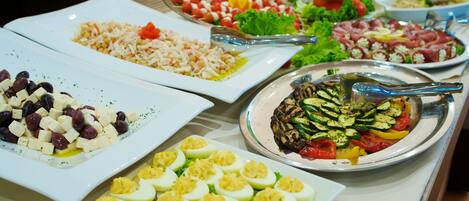 Un bufé con diversos platos, incluyendo ensaladas, verduras y huevos.