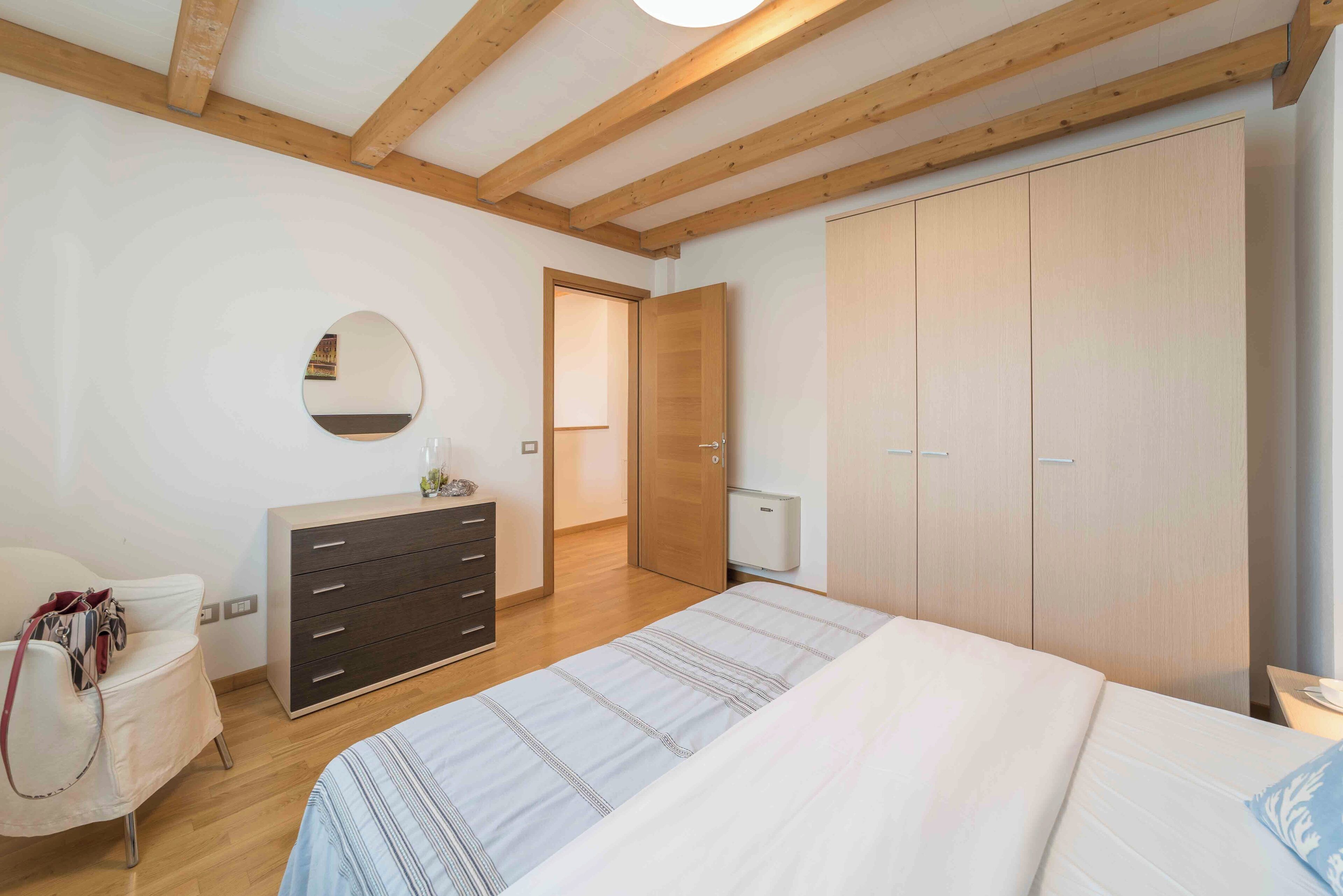 Ein Schlafzimmer mit Bett, Schminktisch, Spiegel und Kleiderschrank.