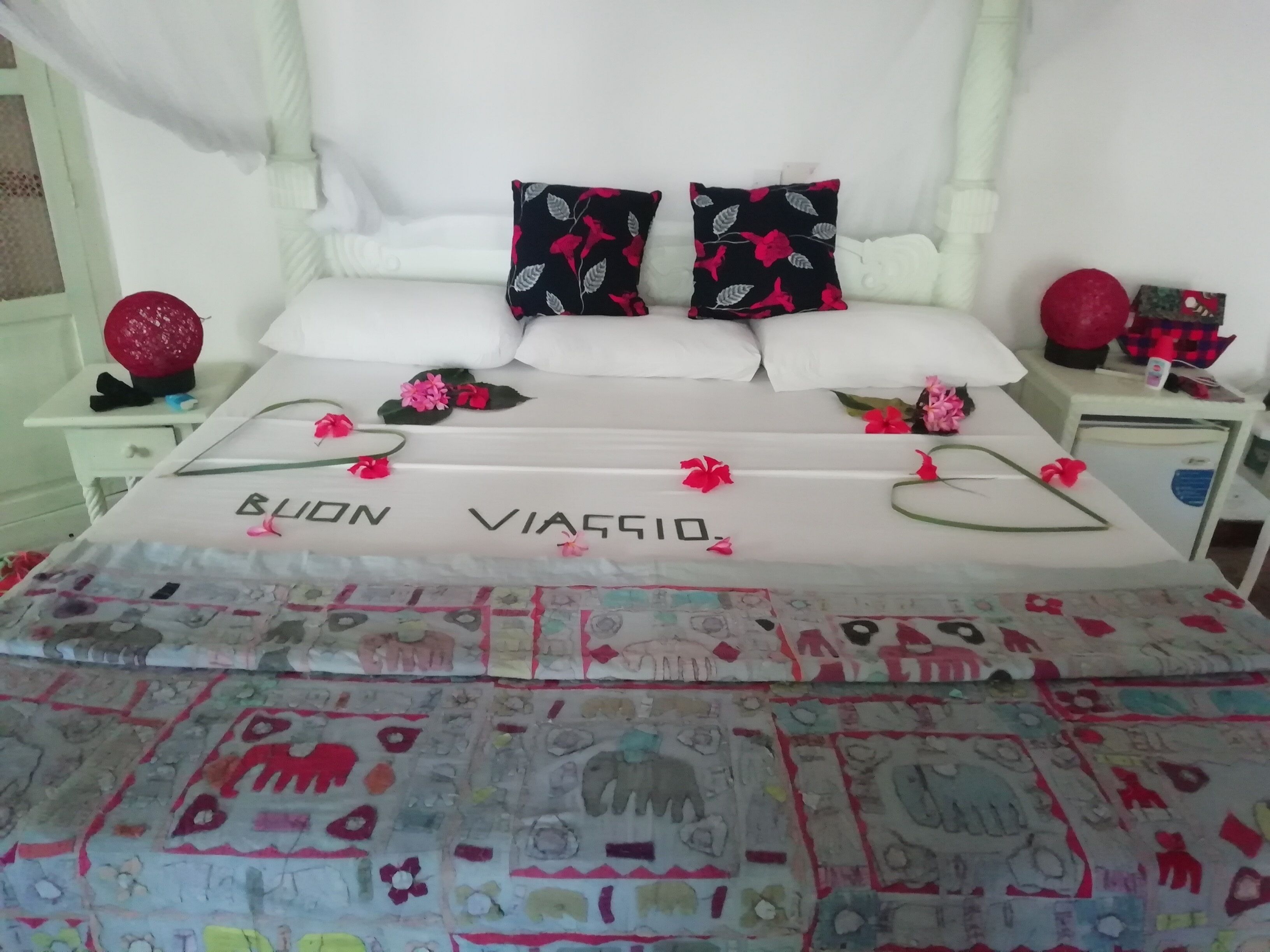 A bed with a floral bedspread and pillows with a black and red floral pattern.
