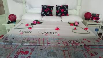 A bed with a floral bedspread and pillows with a black and red floral pattern.
