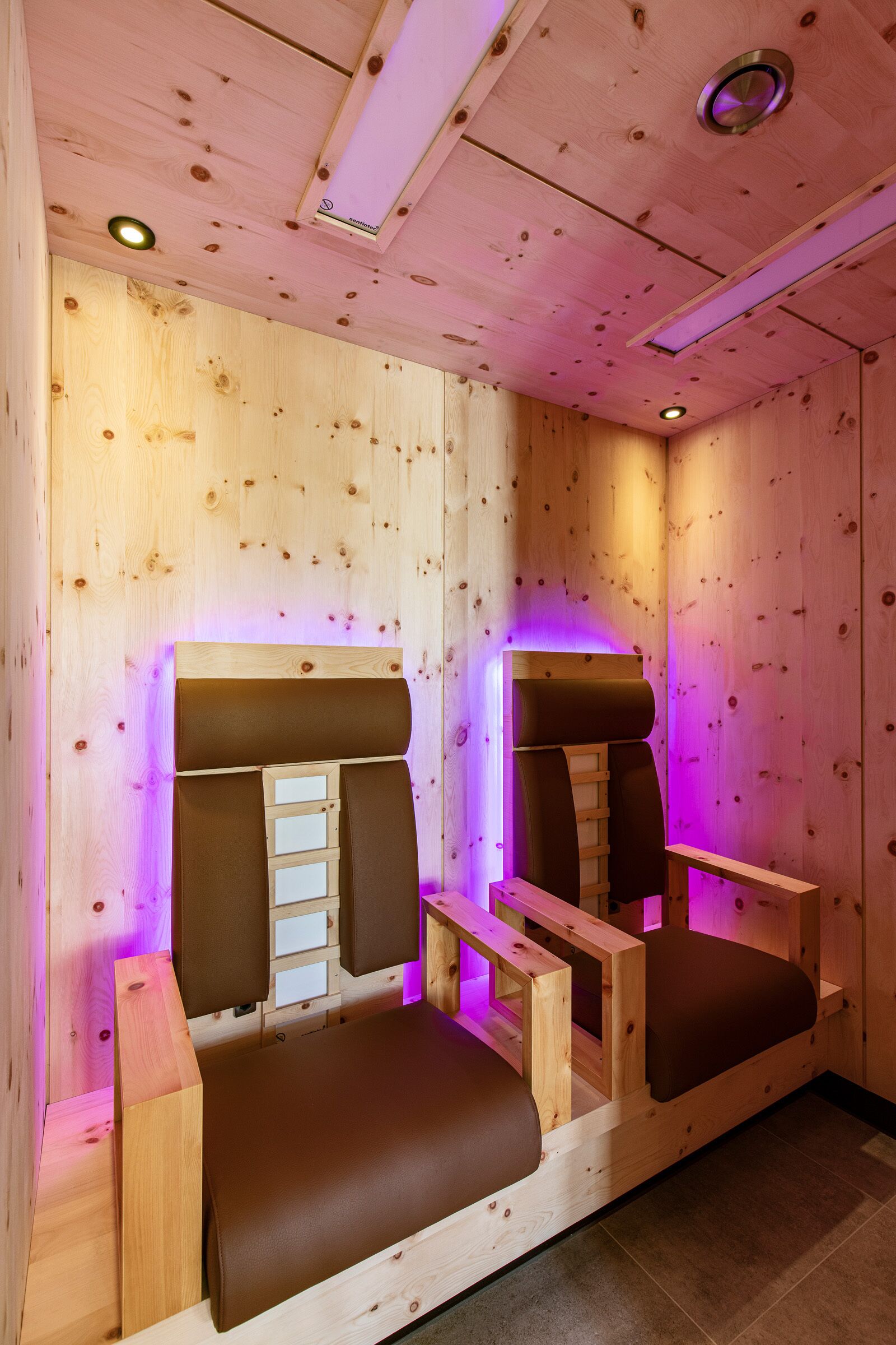 A wooden cabin with two wooden beds and a ceiling light.