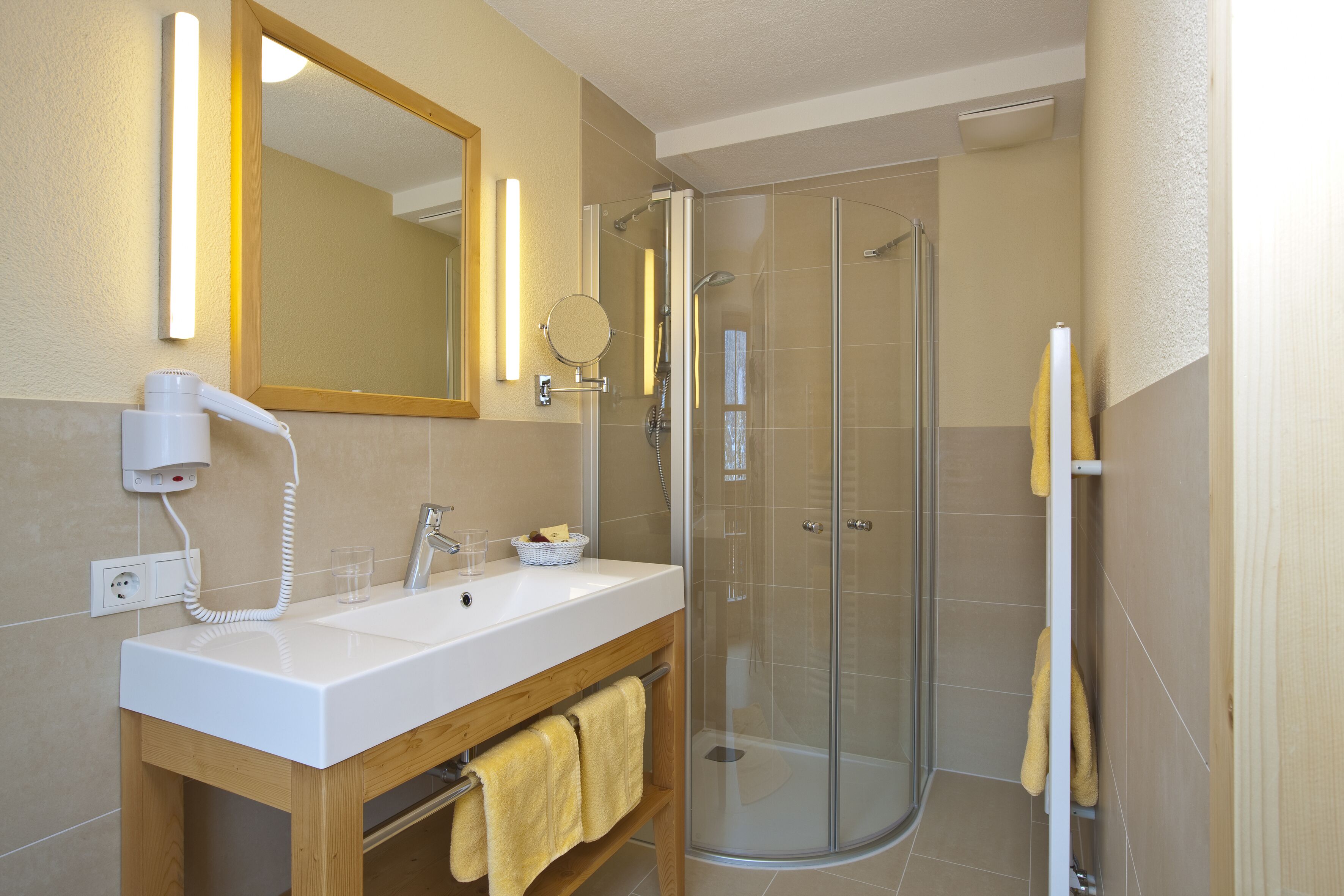 A bathroom with a white sink, mirror, and glass-enclosed shower.