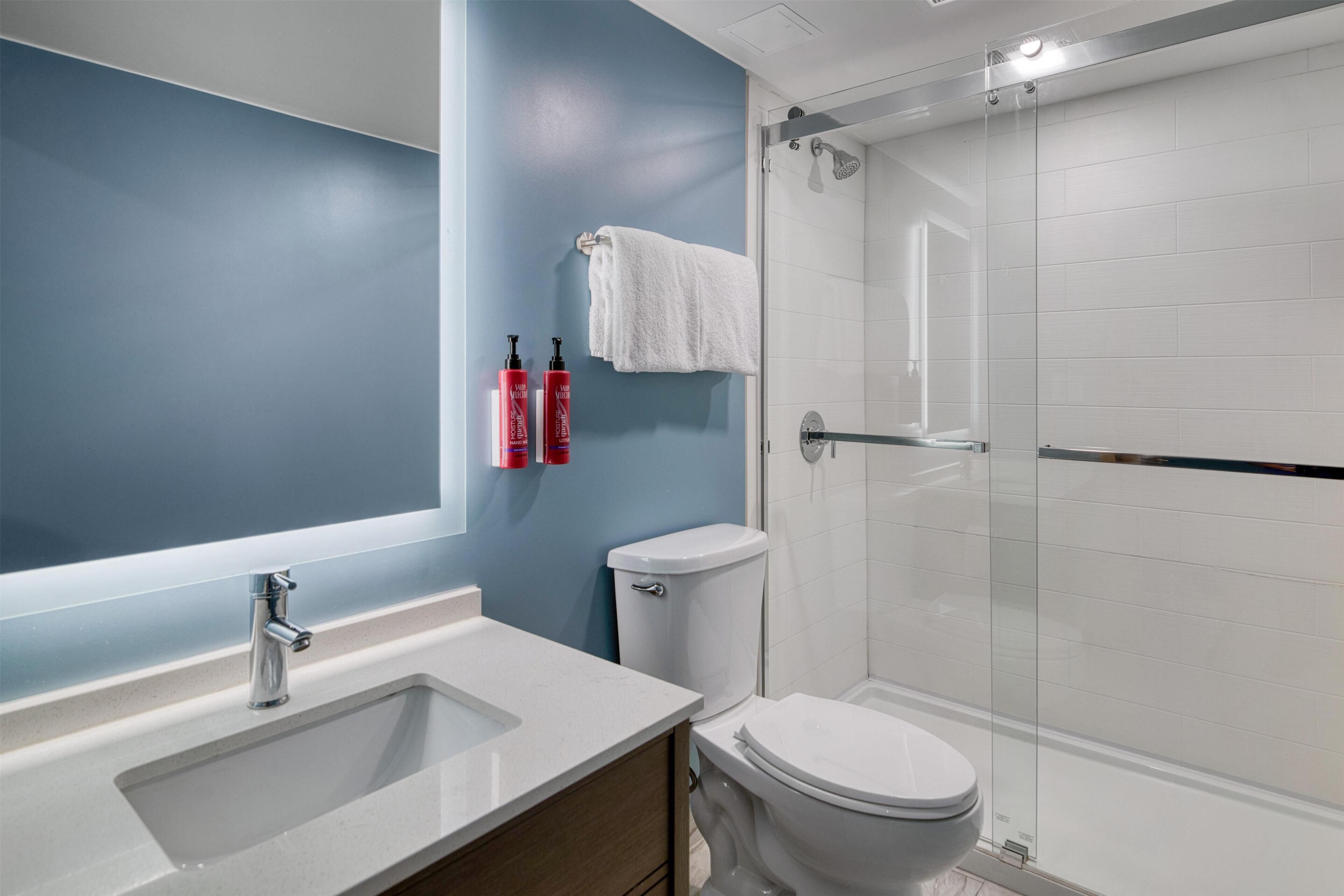 A modern bathroom with a white sink, a toilet, and a glass-enclosed shower.