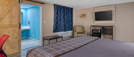 Un dormitorio con cama, escritorio, silla, televisor y microondas.