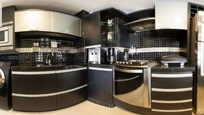 A modern kitchen with black and white cabinetry, a built-in oven, and a coffee maker. - Flat Iate (Fortaleza)