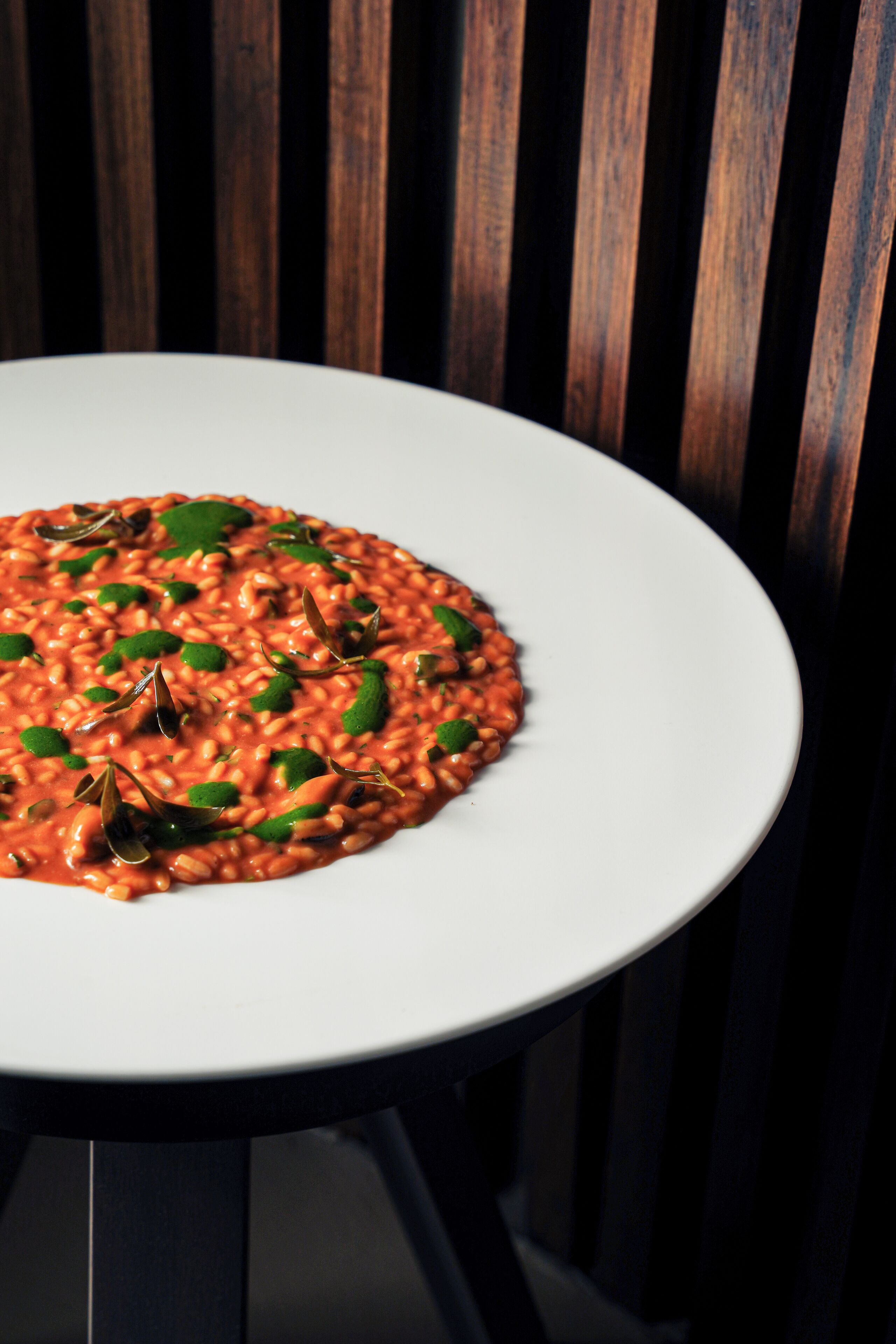 A white plate of pasta with green leaves on a table.