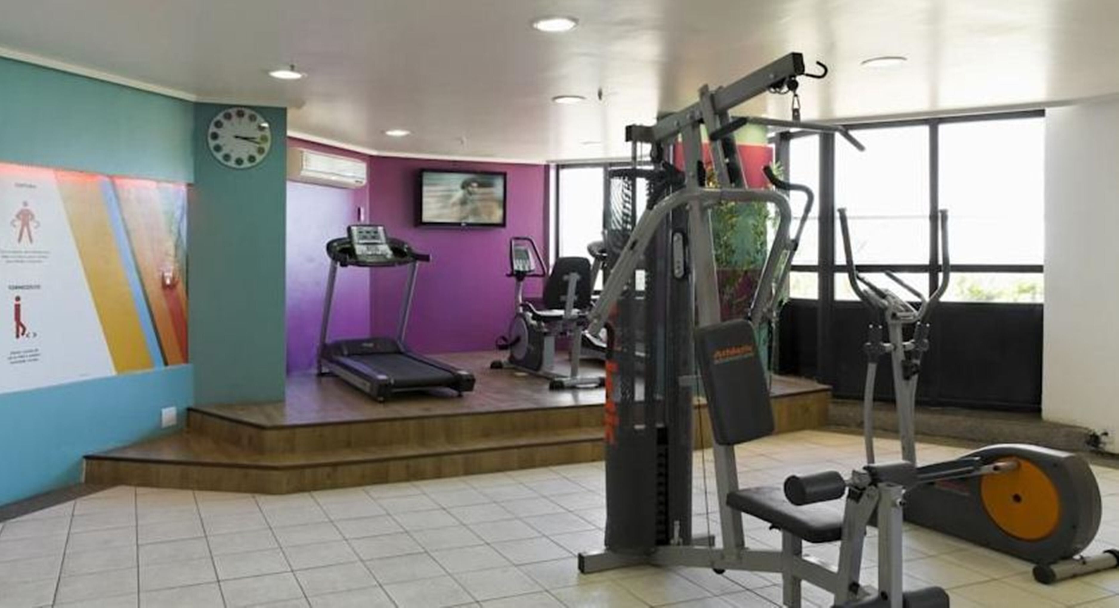 A gym with cardio equipment, a treadmill, and weight machines.
