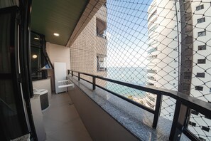 Un balcon avec vue sur la mer, une chaise blanche et une petite table.