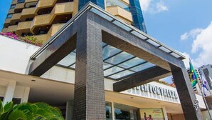 A tall building with a modern design, featuring a glass facade and a structured entrance with a metal canopy. - Flat Golden Fortaleza (Fortaleza)