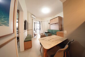 Un espace de vie compact comprenant un coin repas, un canapé et un téléviseur.