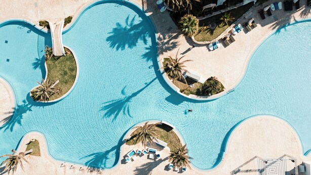 An aerial view of a resort with multiple swimming pools, sun loungers, and palm trees. - ROBINSON DJERBA BAHIYA - All inclusive (Aghir)