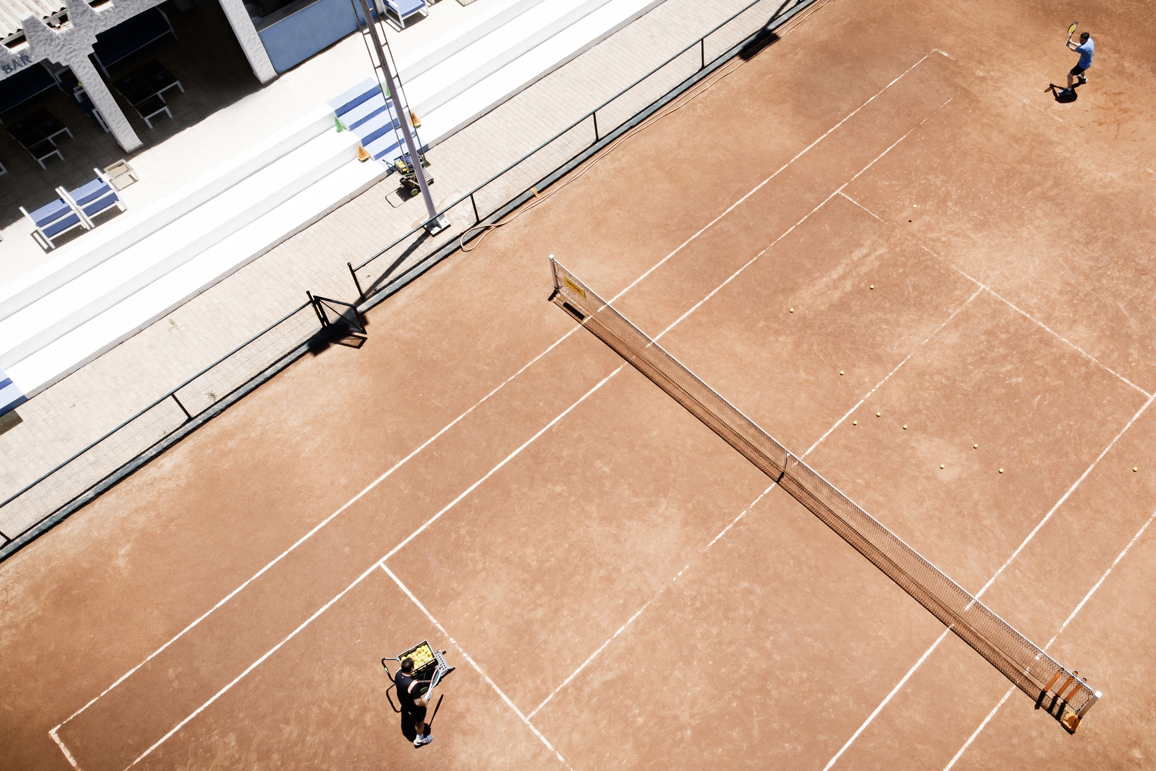 An aerial view of a tennis court with a net, seating area, and spectator stands.